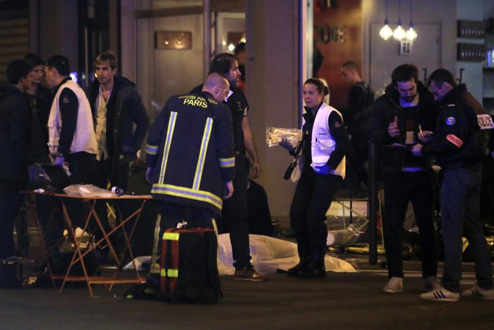Police officers and rescue workers gather around a victim outside a Paris restaurant, Friday, Nov. 13, 2015. Two police officials say at least 11 people have been killed in shootouts and other violence around Paris. Police have reported shootouts in at least two restaurants in Paris. At least two explosions have been heard near the Stade de France stadium, and French media is reporting of a hostage-taking in the capital. (ANSA/AP Photo/Thibault Camus)